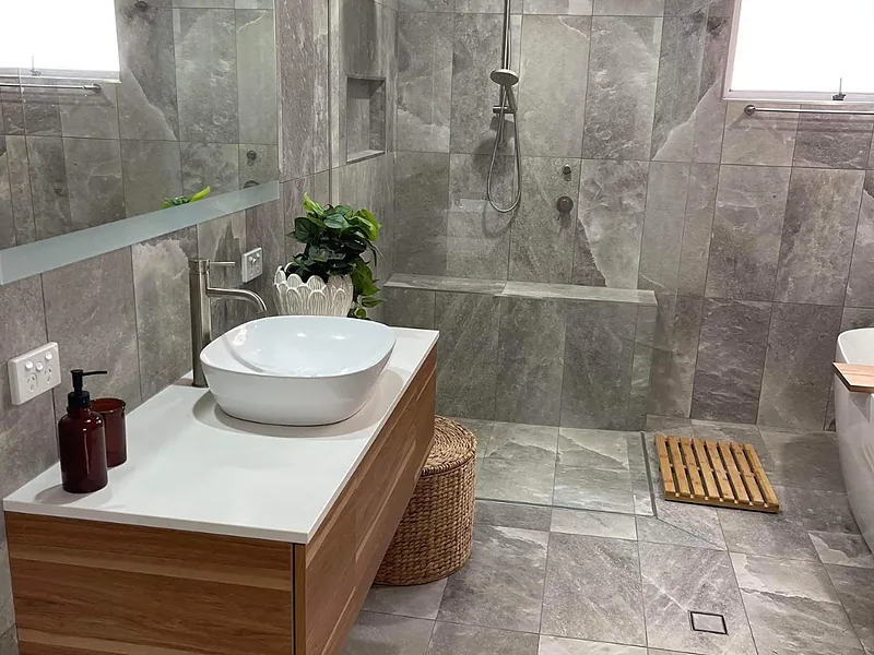 A renovated bathroom with a floating timber vanity, vessel basin and walk-in shower