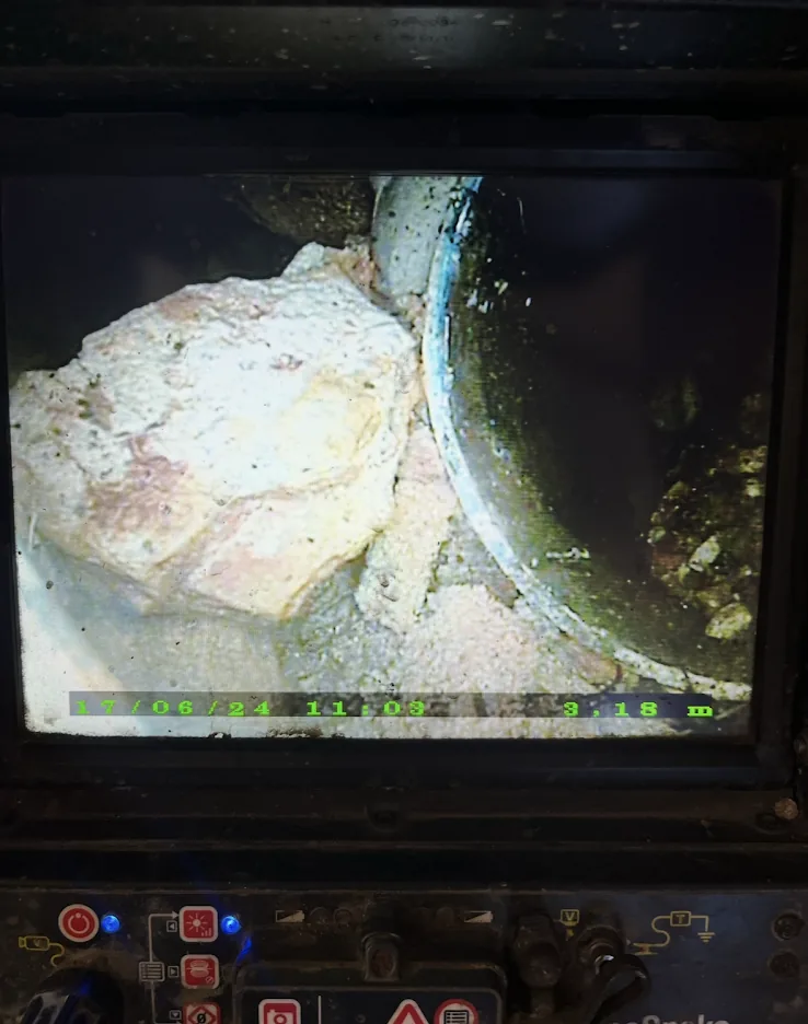 A drain camera screen showing tree roots and debris inside an underground pipe
