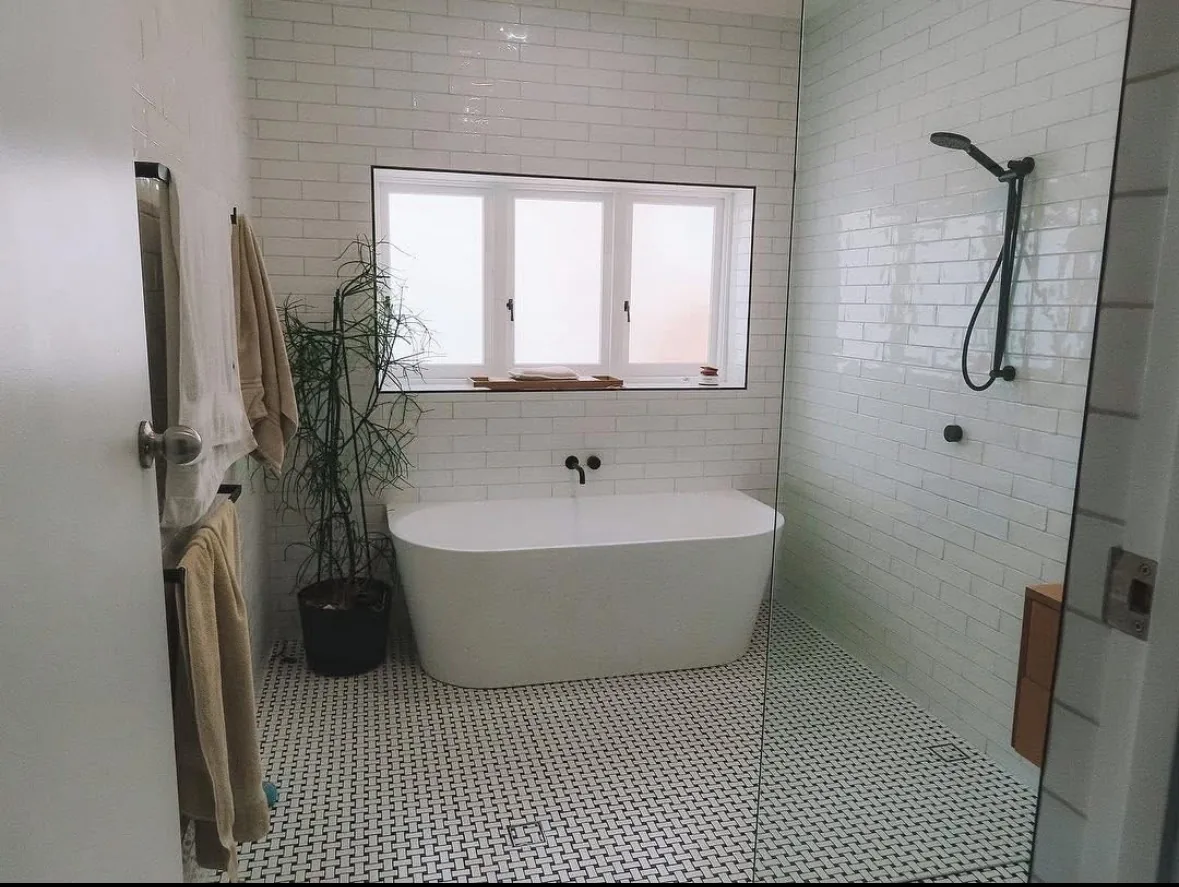 A white bathroom with a freestanding bath, walk-in shower, subway tiles and black tapware