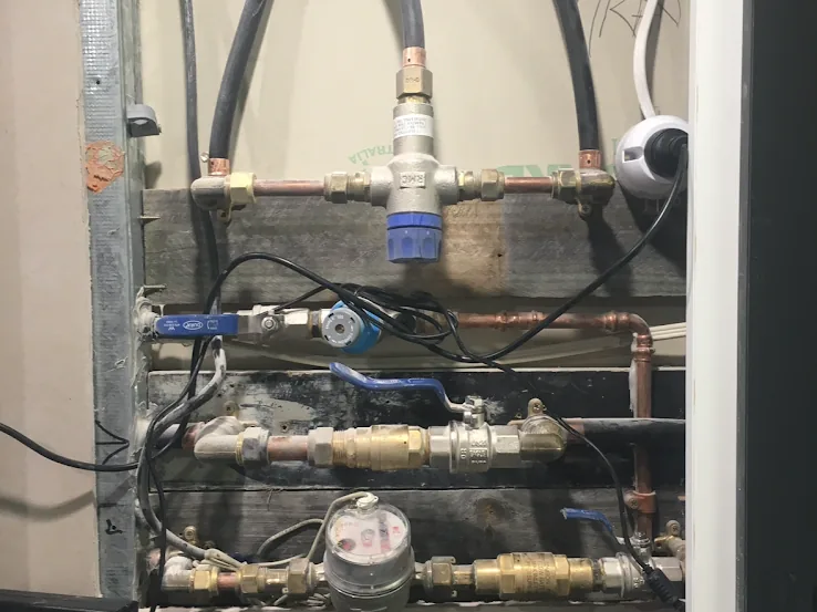 Copper and brass water pipework, valves and meters inside a service cupboard