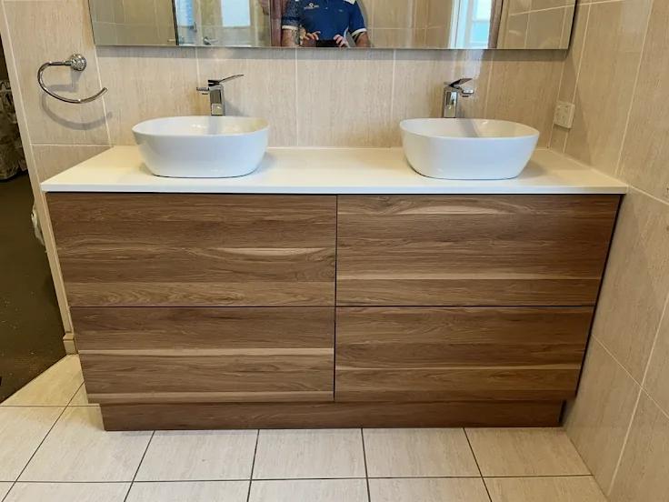 A timber double vanity with two white vessel basins and chrome mixers